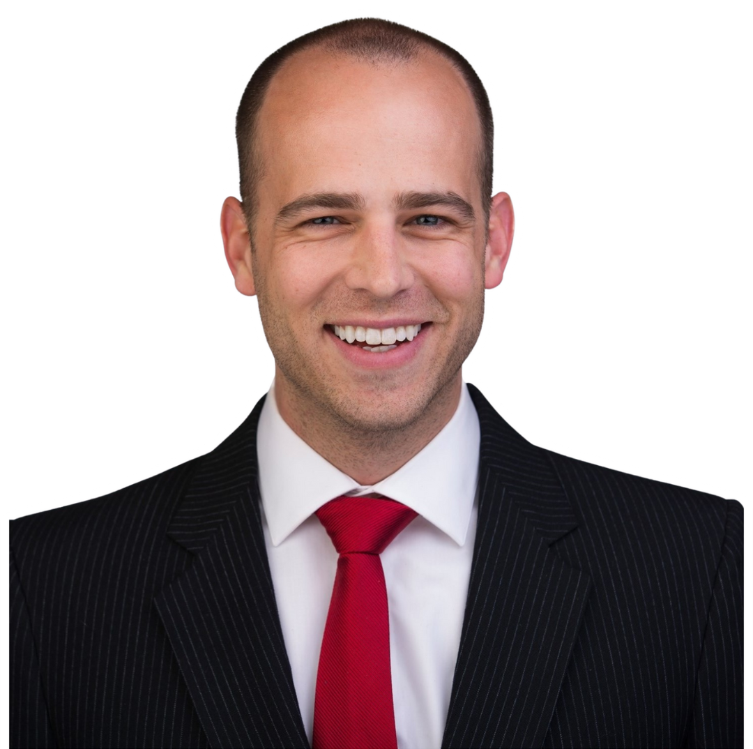 Man in suit, smiling, red tie, bald head.