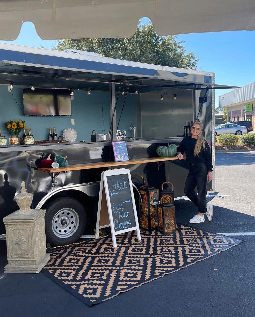 a woman is standing in front of a food truck in a parking lot .