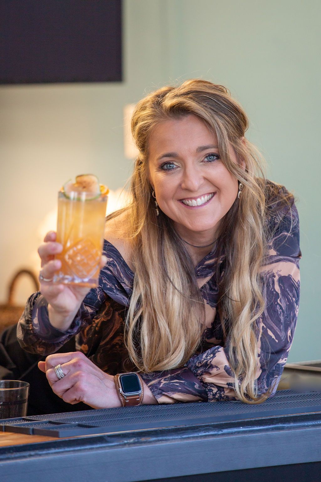 the owner is sitting at a bar holding a drink in her hand