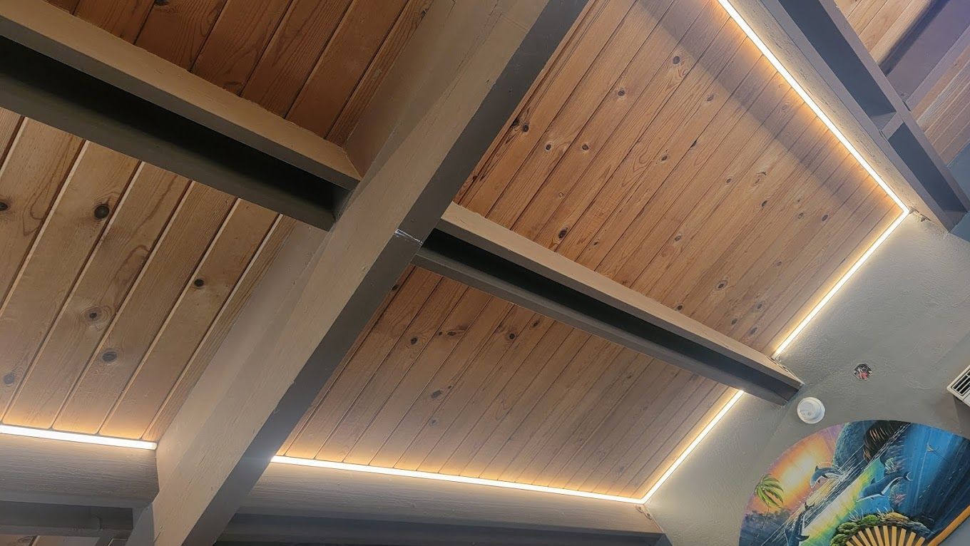 a wooden ceiling with lights on it and a painting on the wall .