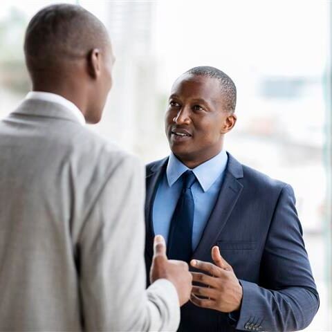 Two men in suits and ties are talking to each other.