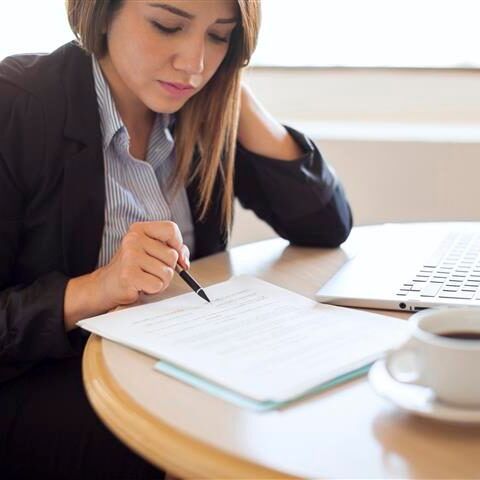 A woman is sitting at a table writing on a piece of paper