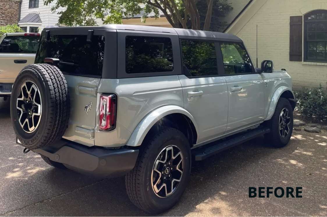 a ford bronco is parked in a driveway in front of a house .