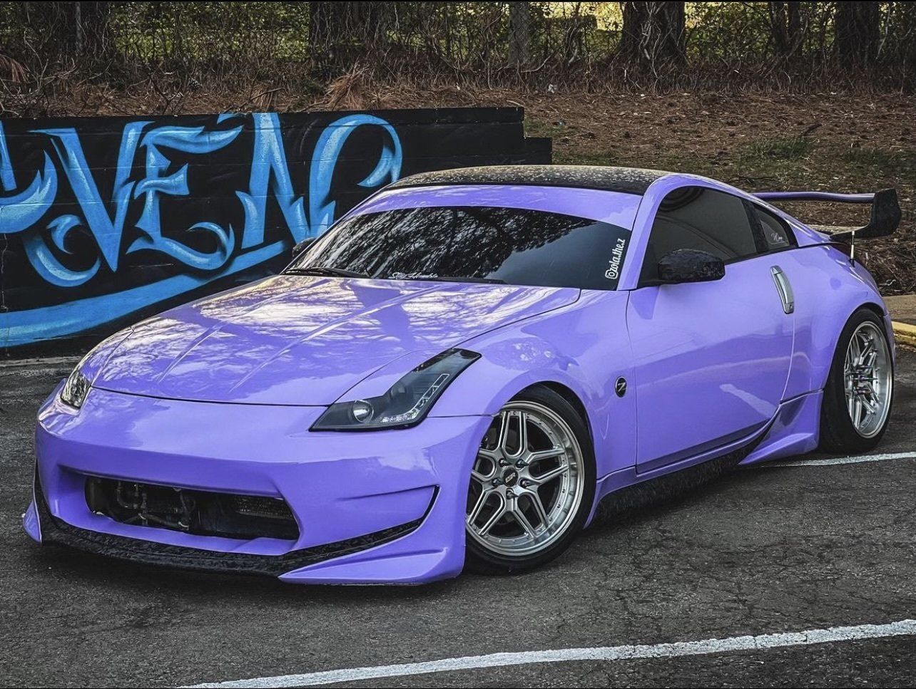 a purple sports car is parked in front of a graffiti wall that says raven