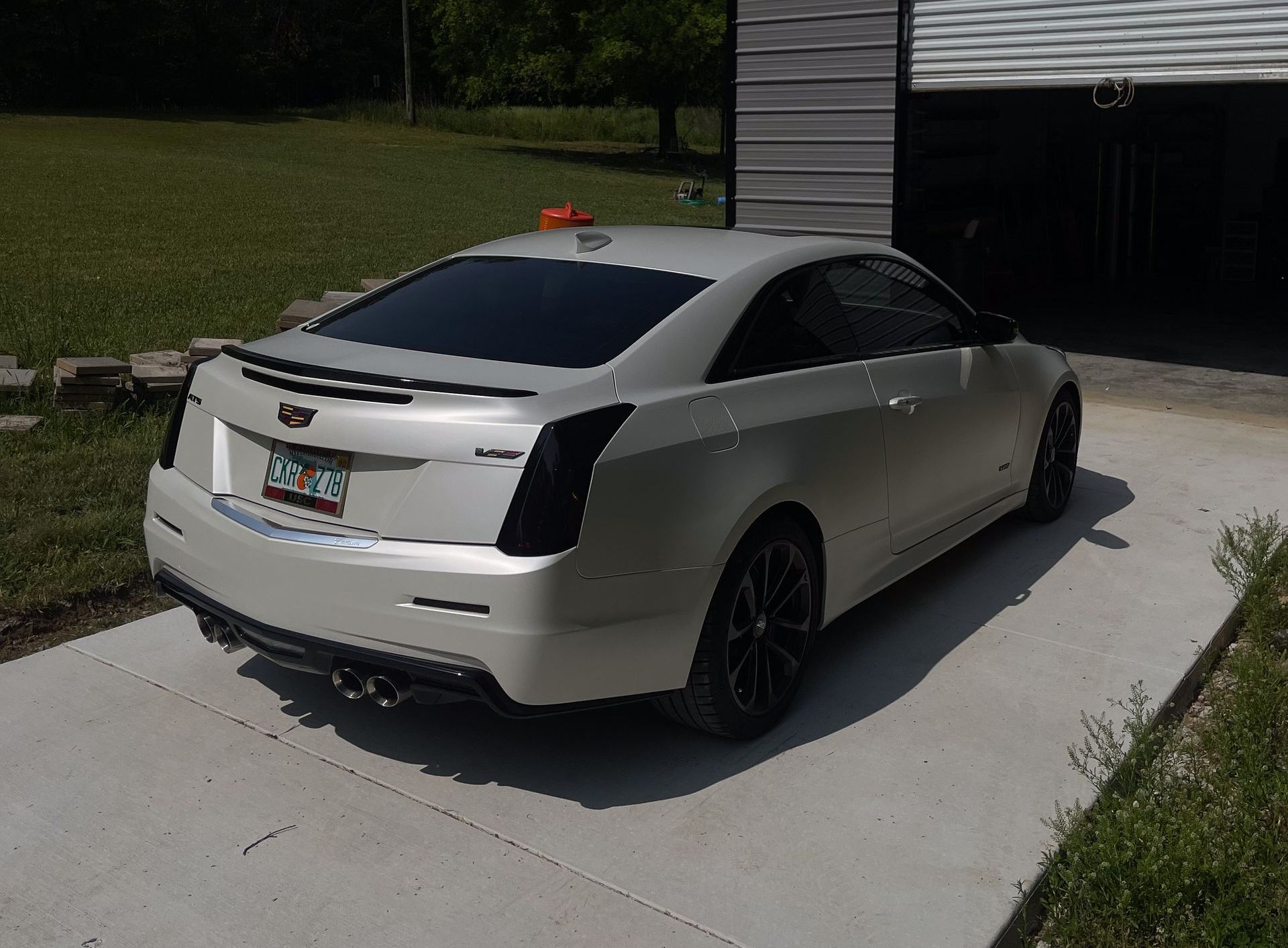 a white cadillac is parked in a driveway in front of a garage