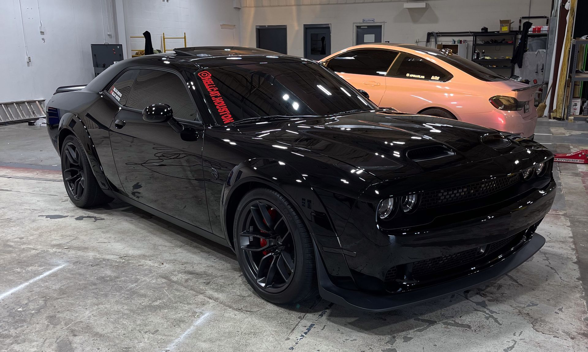 a black Dodge Challenger is parked in a garage.