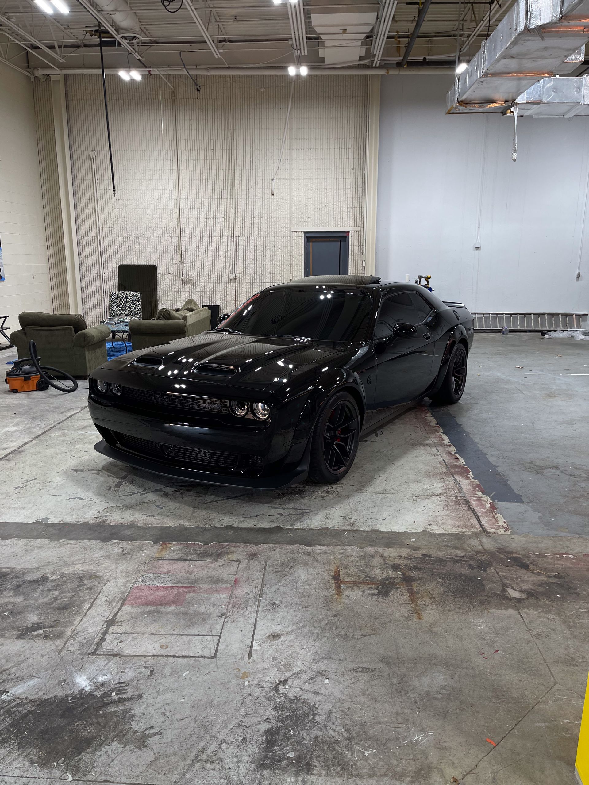 a black dodge challenger is parked in a garage.