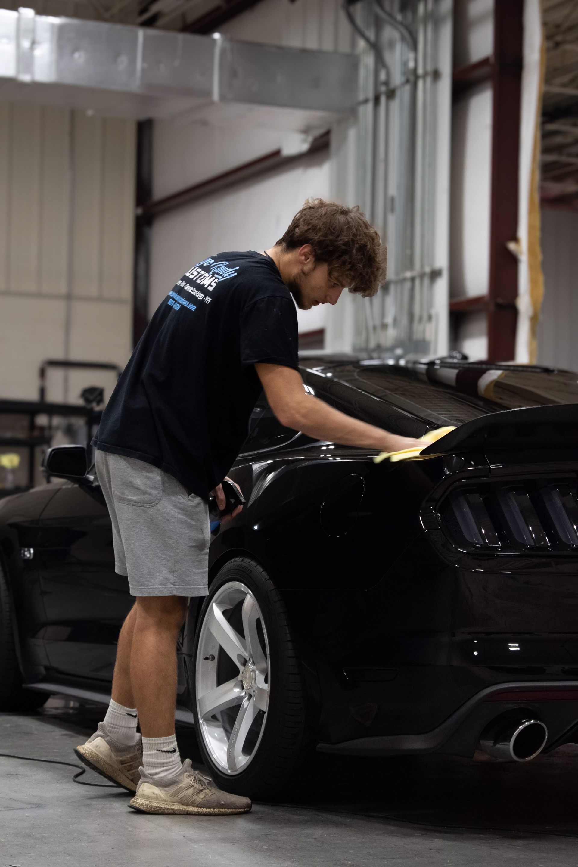 a man is polishing a black car in a garage .
