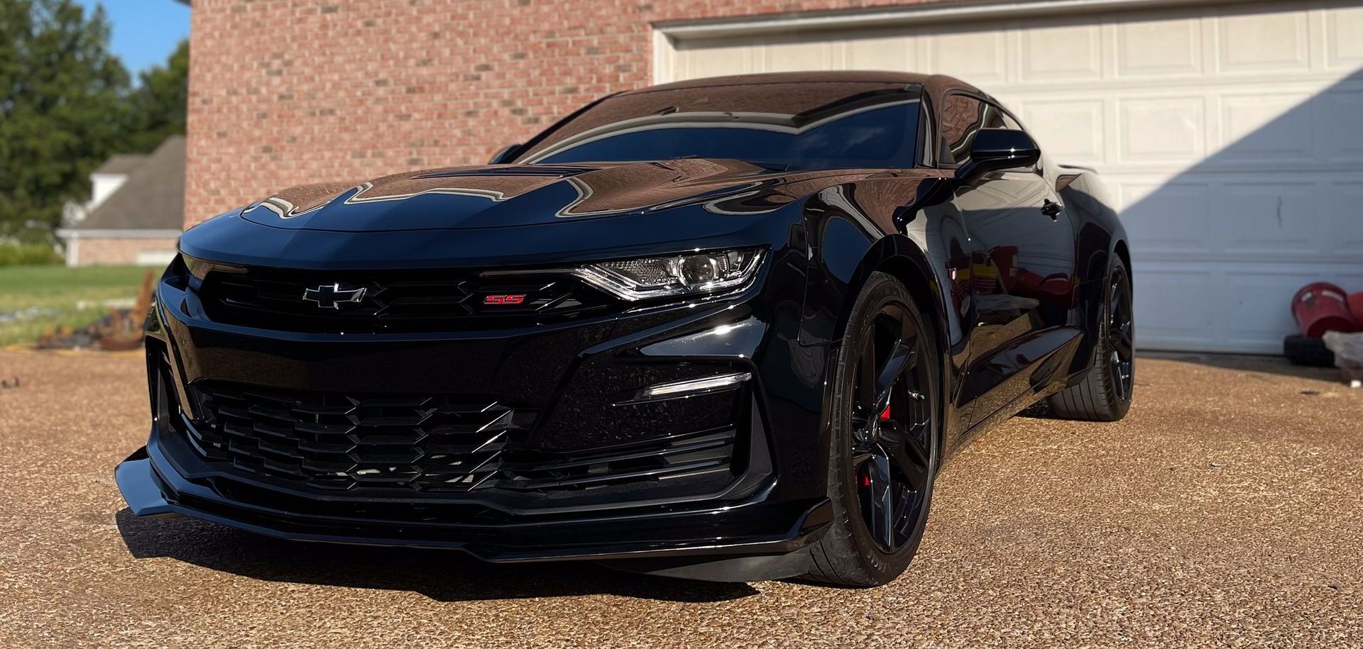 a black camaro SS is parked in front of a garage door.