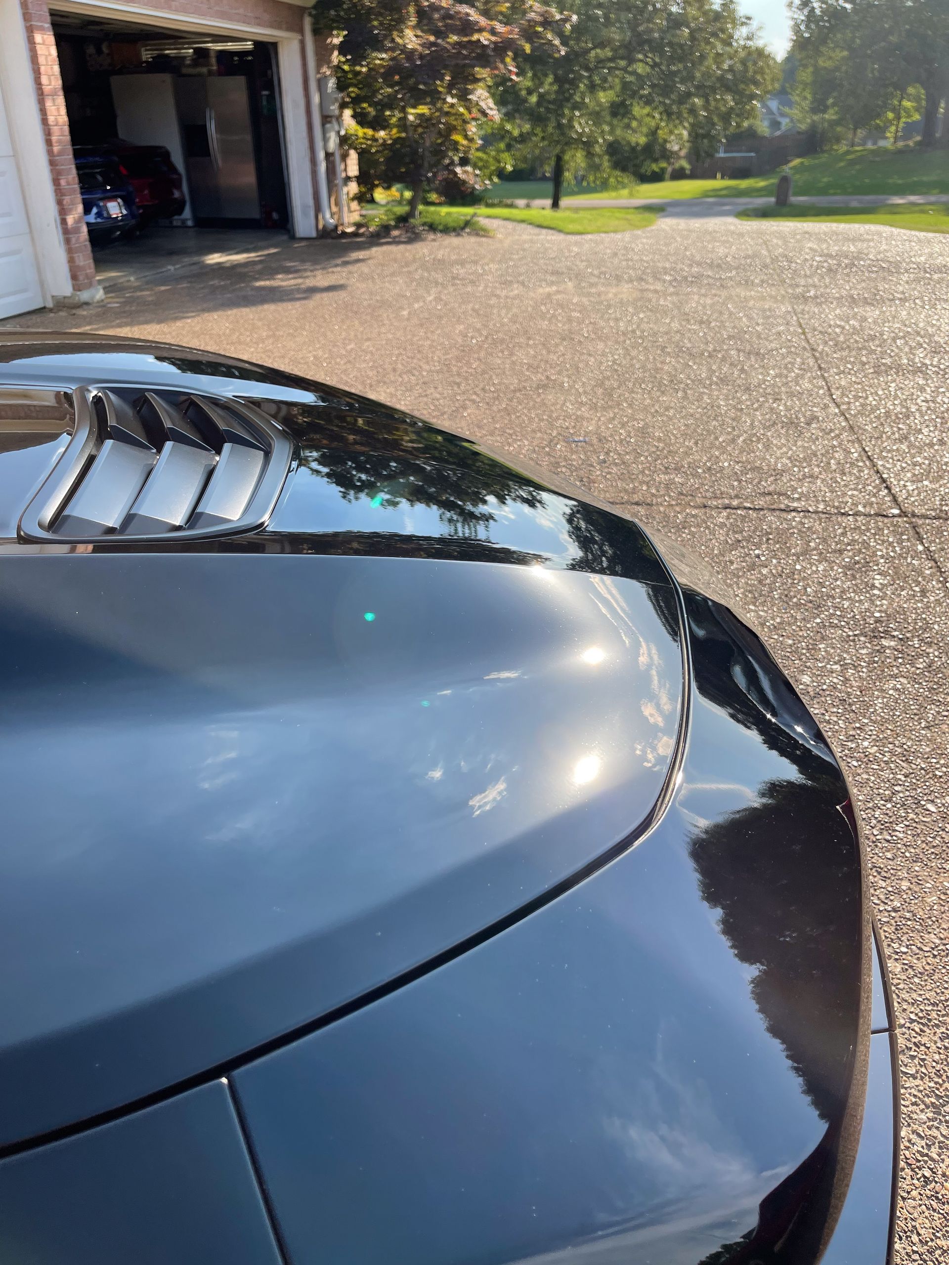 a black car is parked in a driveway next to a garage.