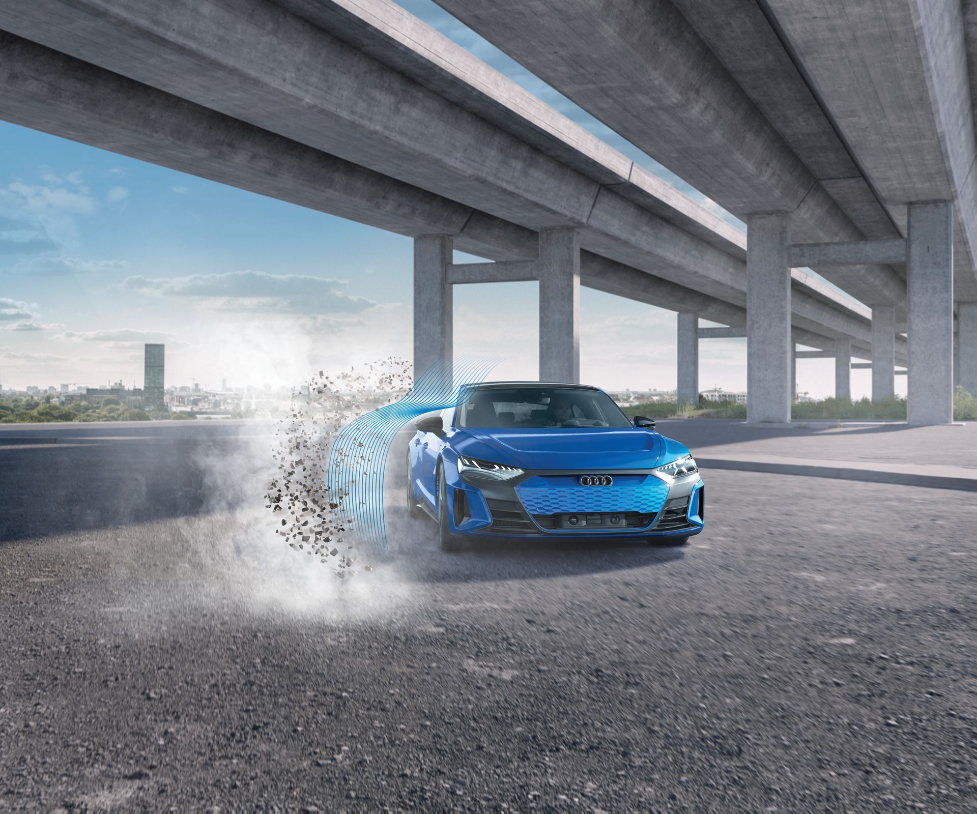 a blue sports car is parked under an underpass in a gravel parking lot