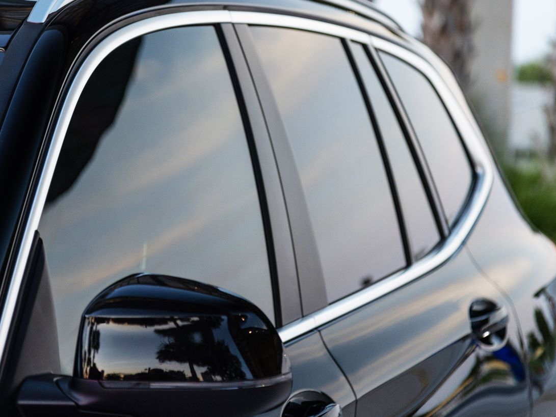 Close-up of a car with tinted windows, showcasing the sleek, dark film applied to the glass.