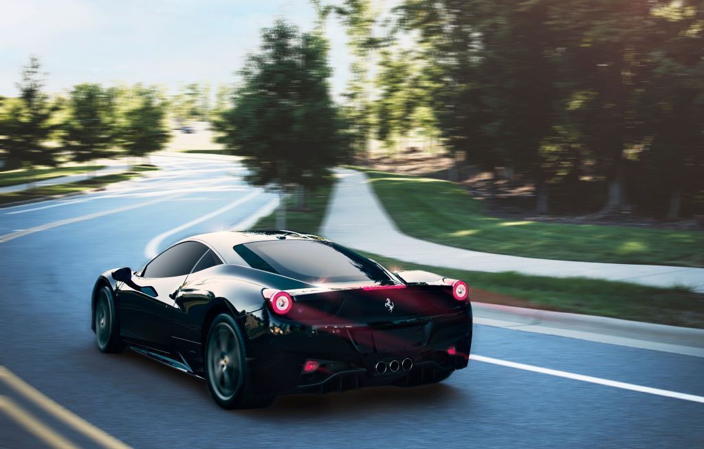 Aerial view of a Ferrari with tinted windows driving towards the sunset