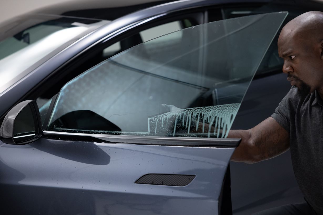 A man cleaning a tinted car window