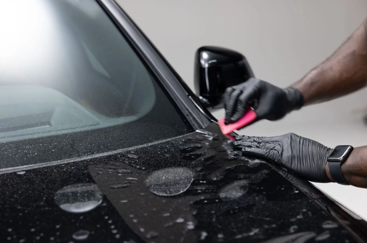 Technician applying Paint Protection Film (PPF) to a car.