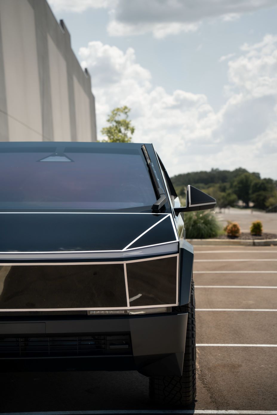 Close-up view of the front half of a Cybertruck with custom gloss black PPF and 3M reflective pinstriping on the bevels and body lines