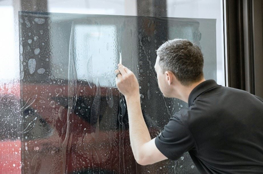 Technician carefully applying window tint film