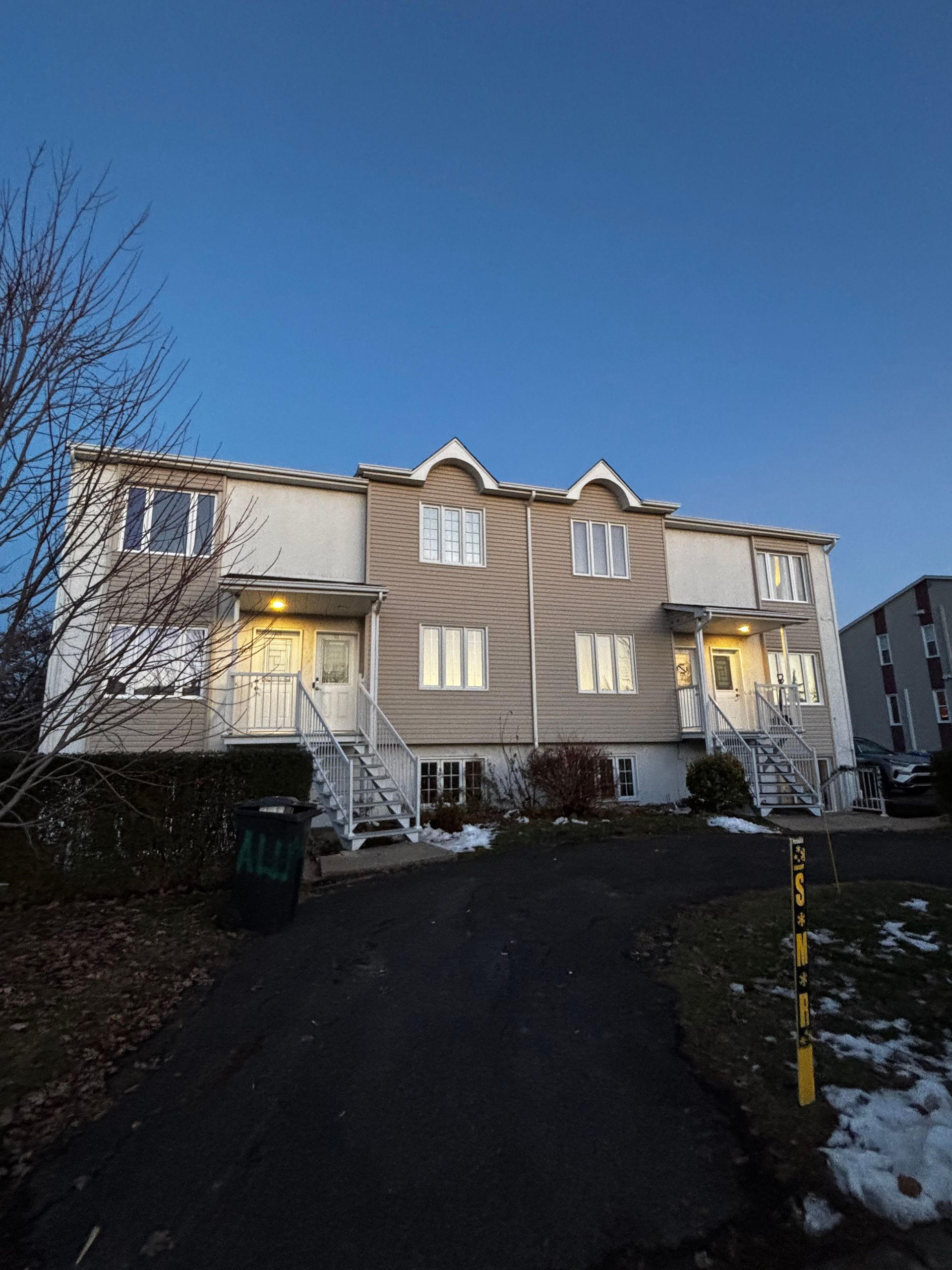 Maisons de ville aux murs blancs et à l'allée sombre se détachant sur un ciel bleu.