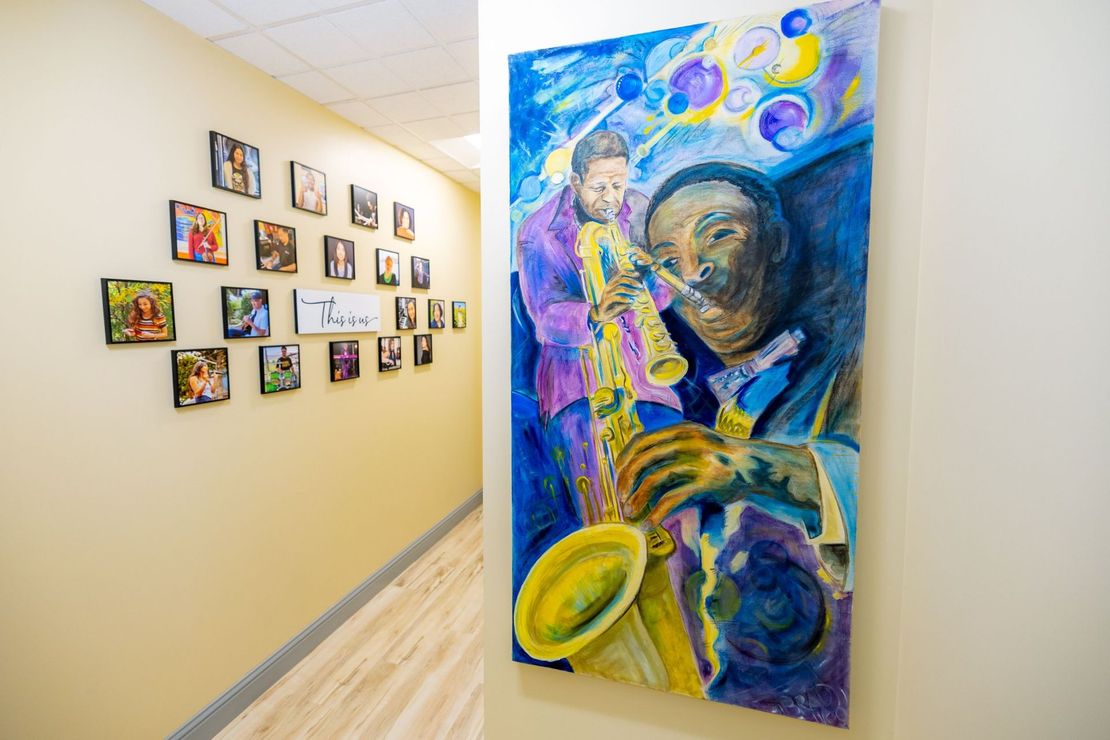 A painting of a man playing a saxophone is hanging on a wall in a hallway.