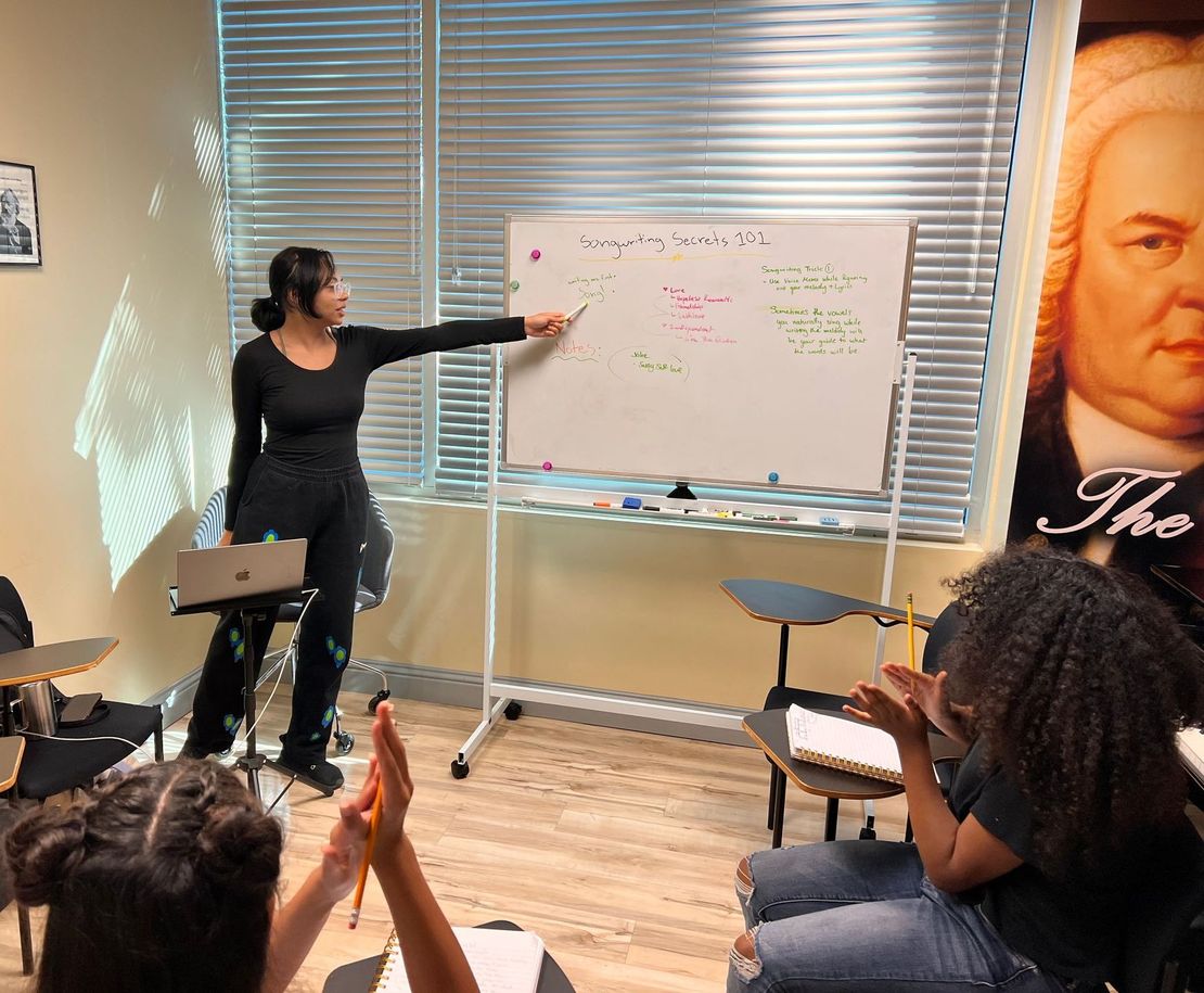 A woman is giving a presentation to a group of students in a classroom.