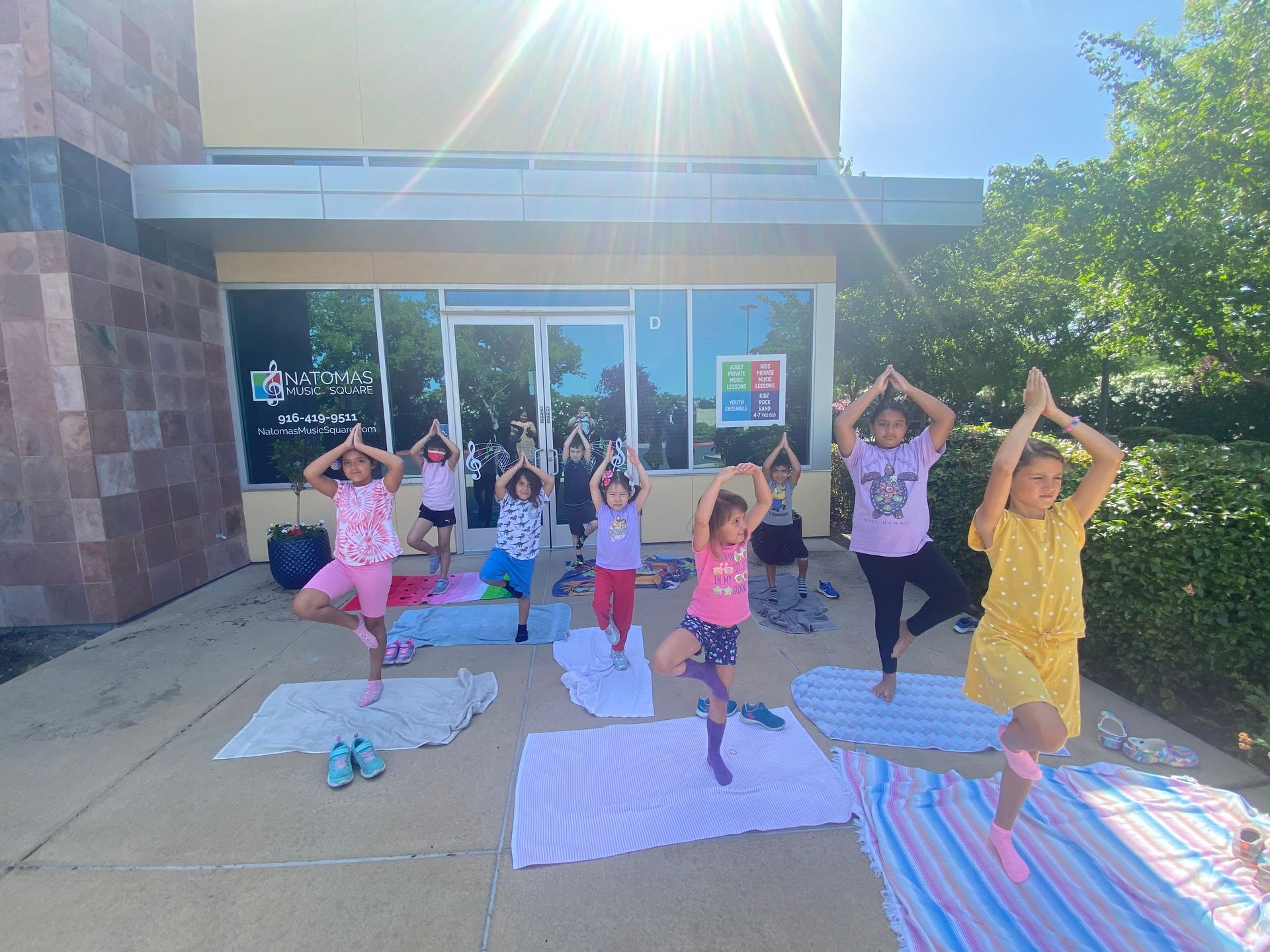 A group of young girls are doing yoga outside of a building.