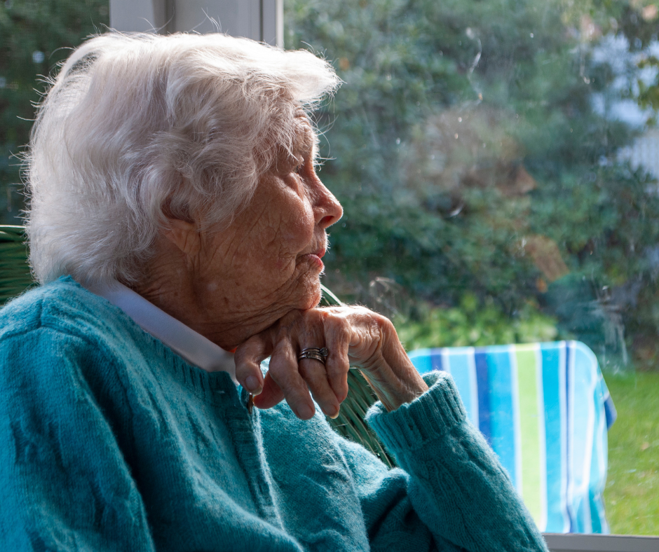 Elderly woman looking out a window.