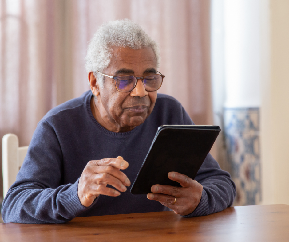 Elderly man reading on a tablet.