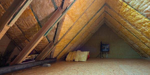 An attic with wooden beams and insulation on the ceiling.