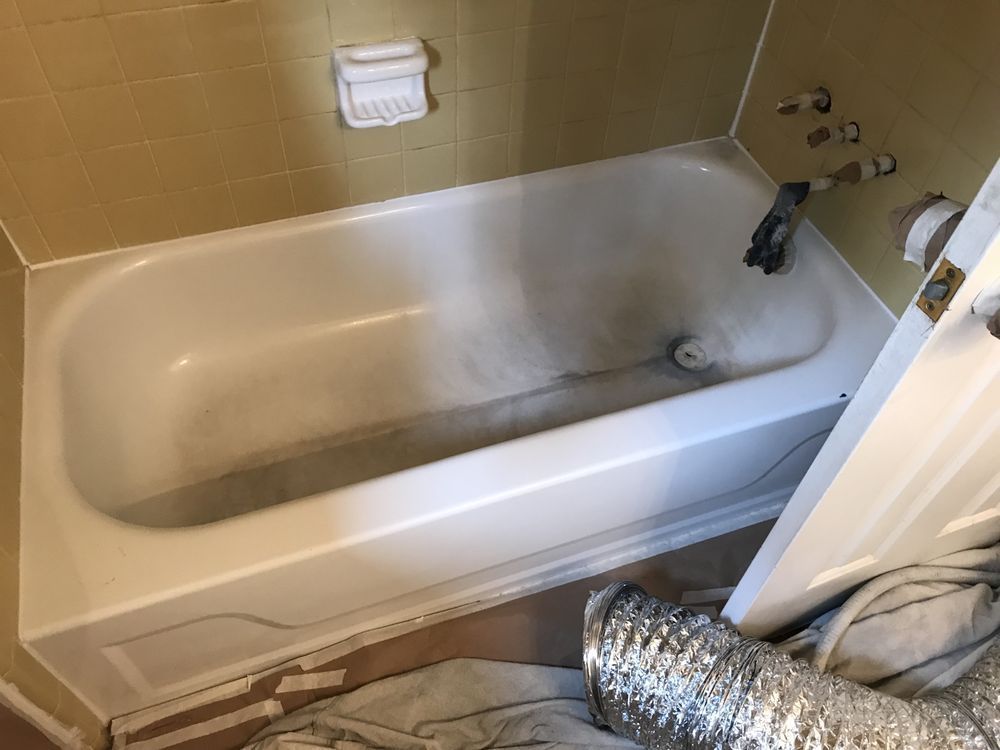 Empty bathtub with beige tile walls and a chrome faucet, viewed from the bathroom doorway.