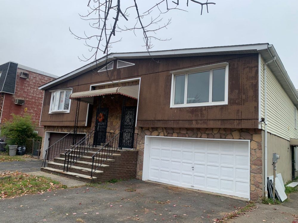 Single-family house with front steps, covered porch, and attached garage on a cloudy day