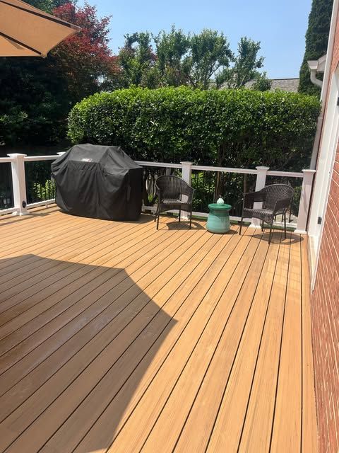 Wooden deck with seating, potted plants, and a screened-in porch, overlooking a wooded area.