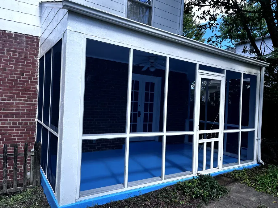 Screened porch with blue floor, white frames, and brick wall.