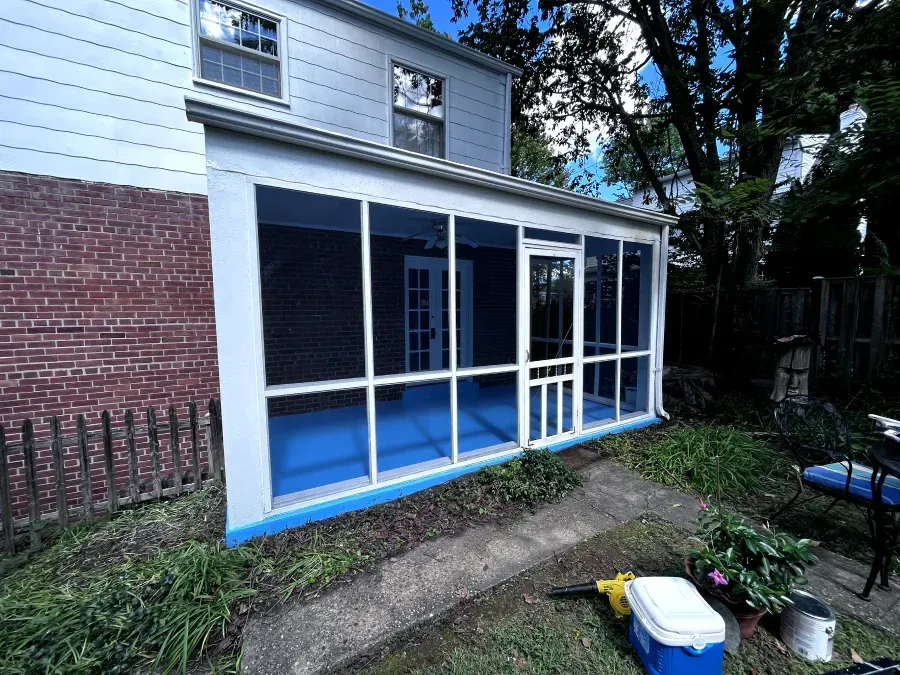 Screened-in porch attached to a two-story house, with a blue floor and white trim.