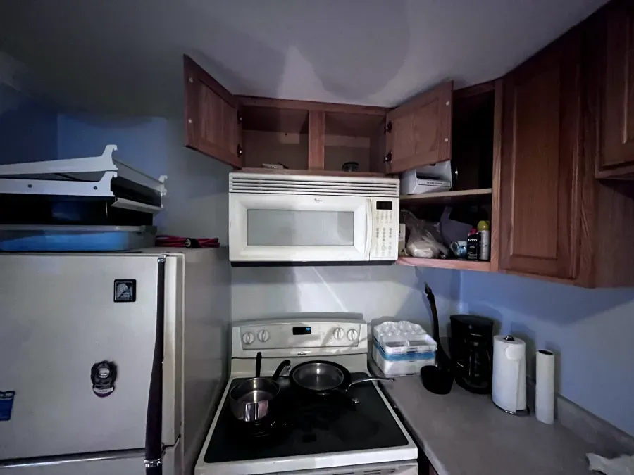 Kitchen with open cabinets above a microwave and stove, with a fridge and counter.