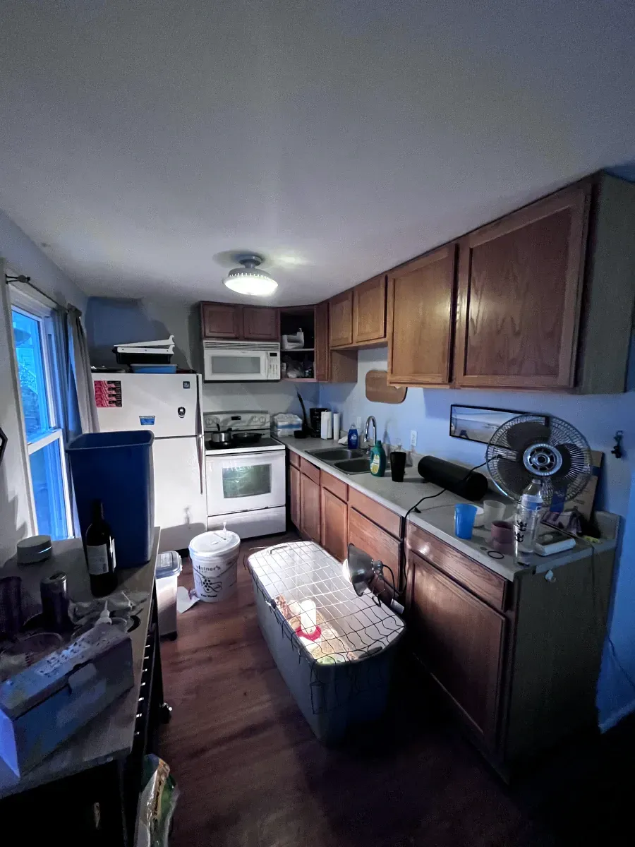 Kitchen with wooden cabinets, appliances, and a trash bin.