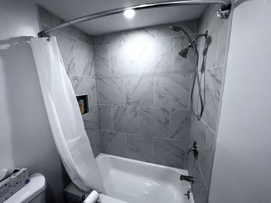 Bathroom with gray marble tile, shower curtain, and fixtures.