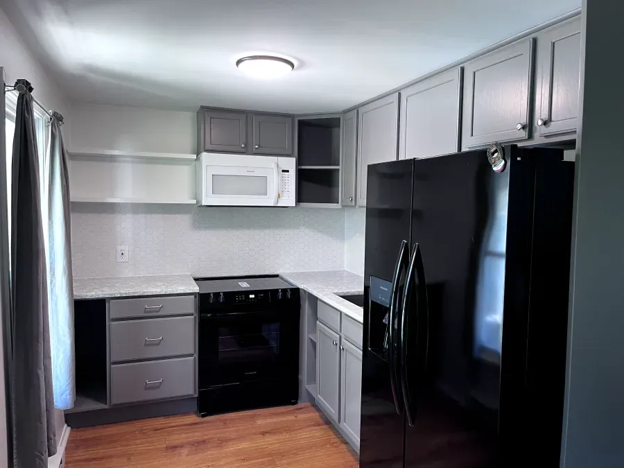 Gray kitchen cabinets, black appliances, white backsplash.