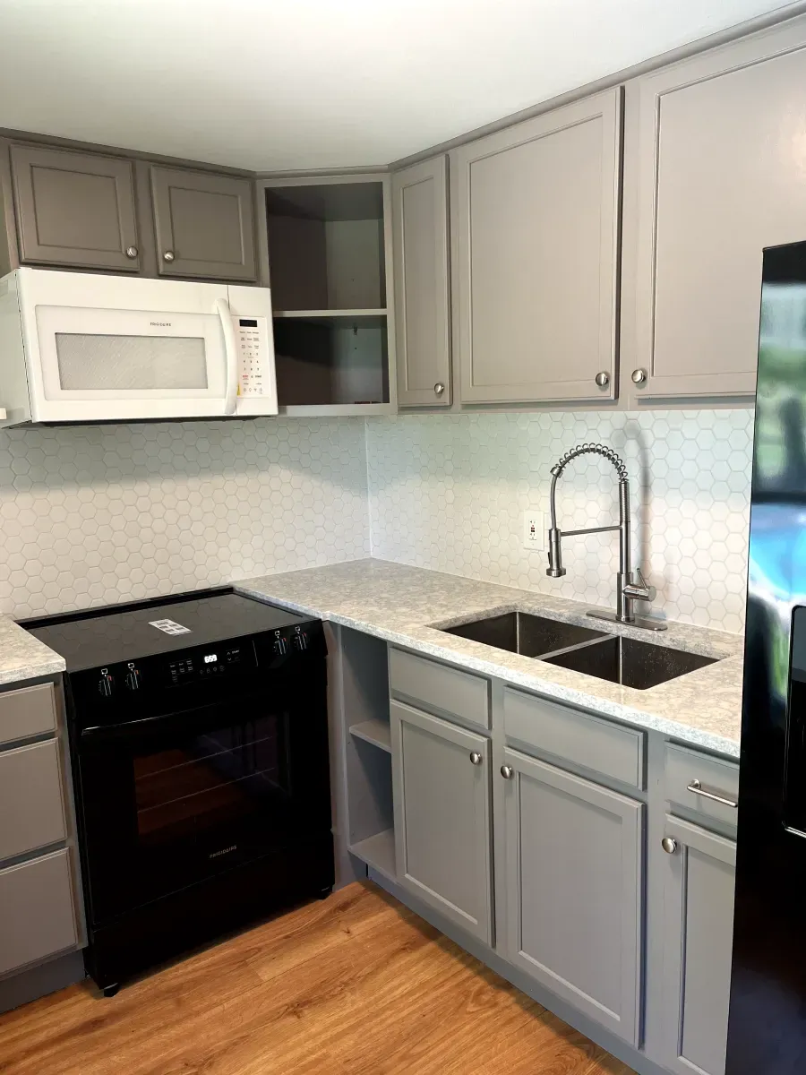 Gray kitchen with black oven, white microwave, and stainless steel sink.