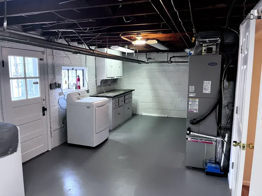 Laundry room with white appliances, gray floor, and a furnace.