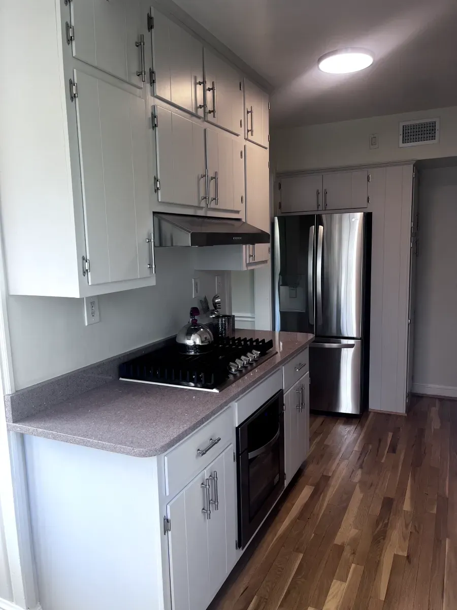 Kitchen with white cabinets, gas cooktop, stainless steel appliances, and hardwood floors.