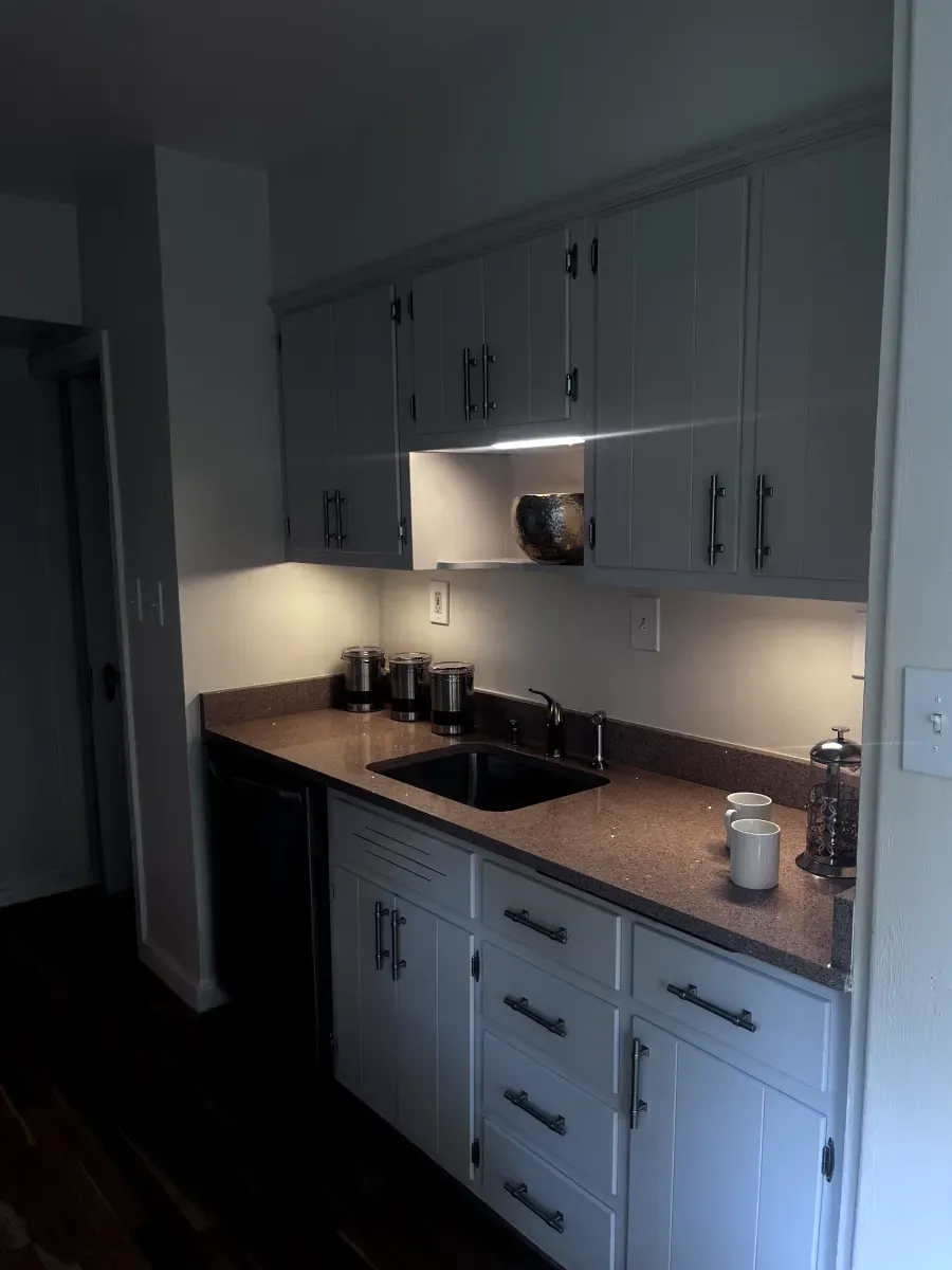 Small kitchen with white cabinets, brown countertop, and black sink and appliances.