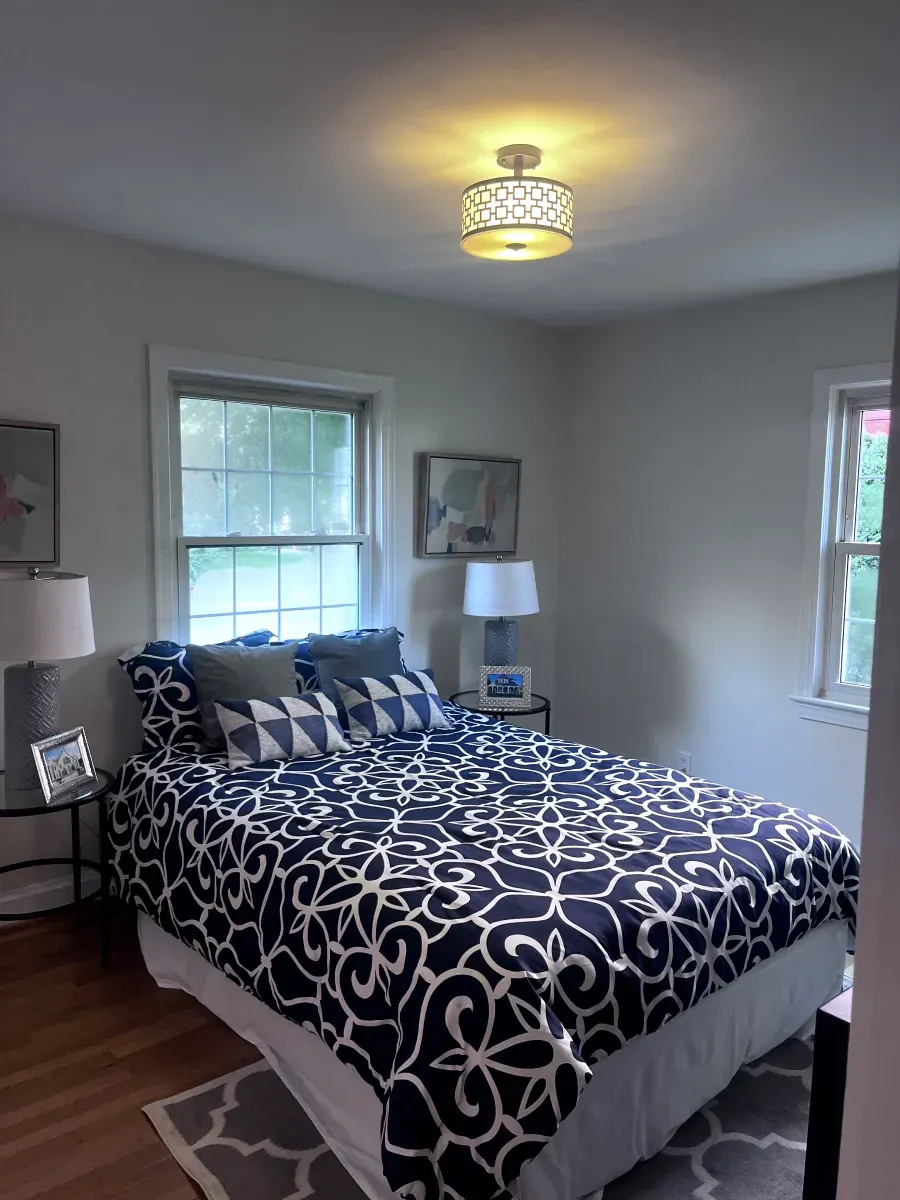 Bedroom with blue and white patterned bedding, a window, and a decorative ceiling light.