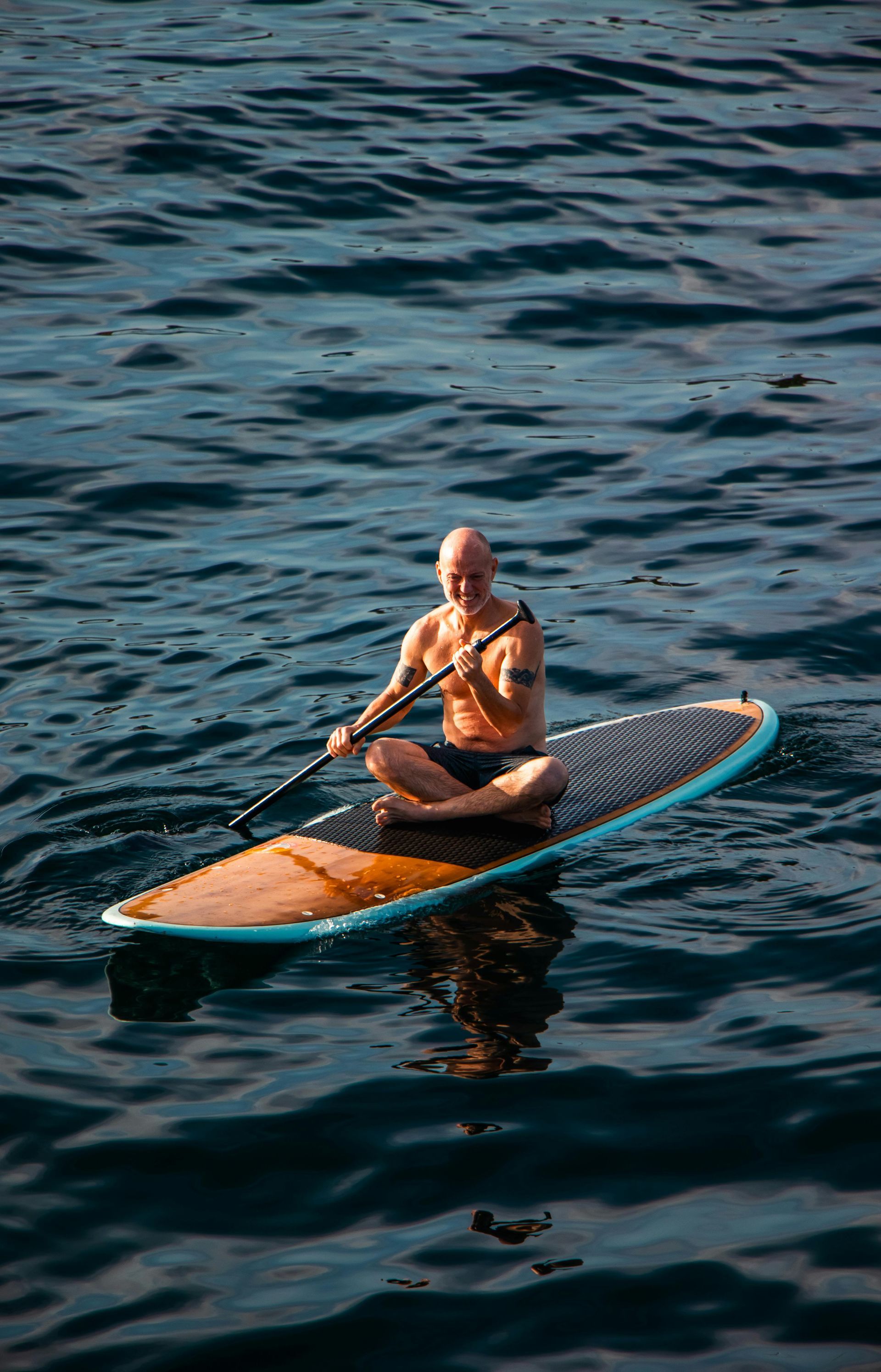 Un hombre está sentado en una tabla de remo en el océano.