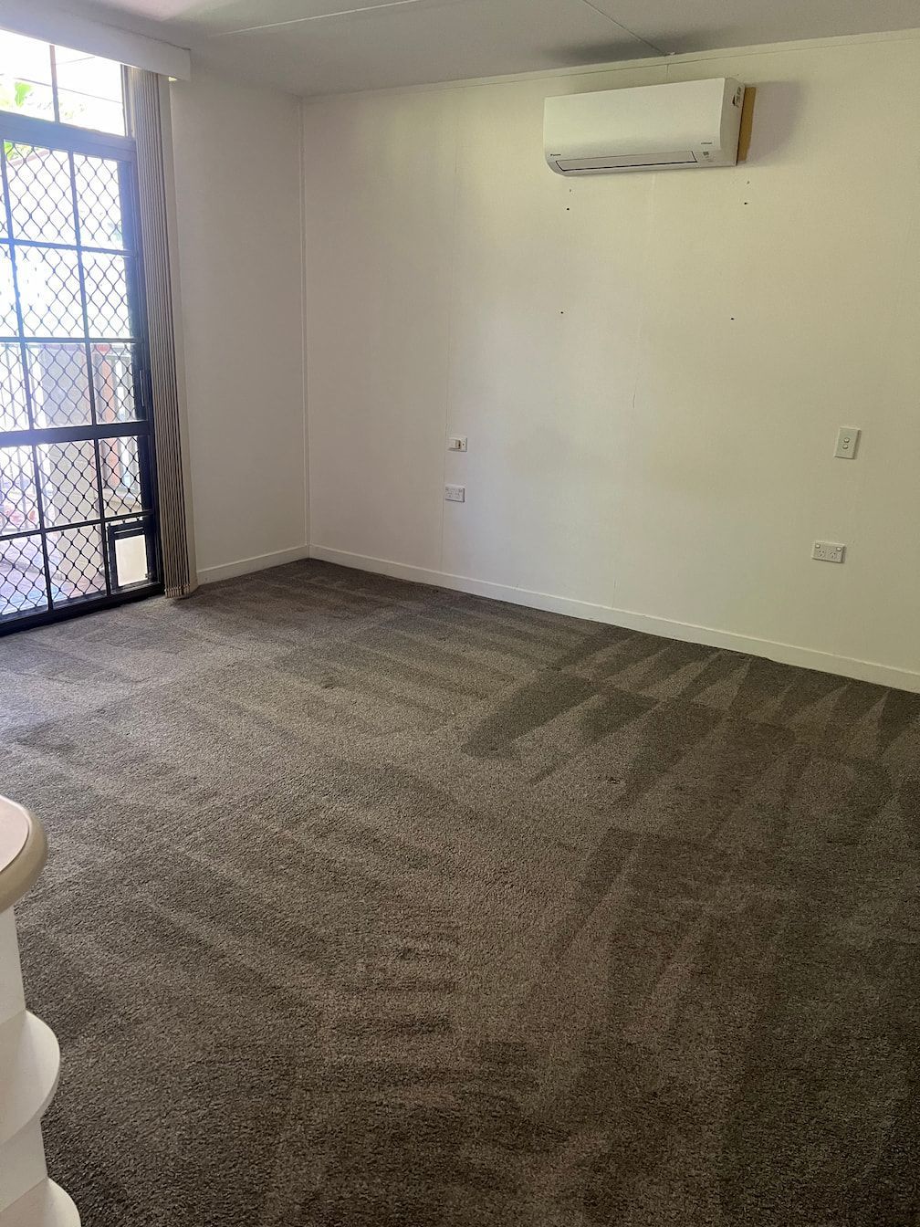 An Empty Living Room With A Carpeted Floor And A Window — Miss Bright Cleaning Services In Mount Isa City, QLD