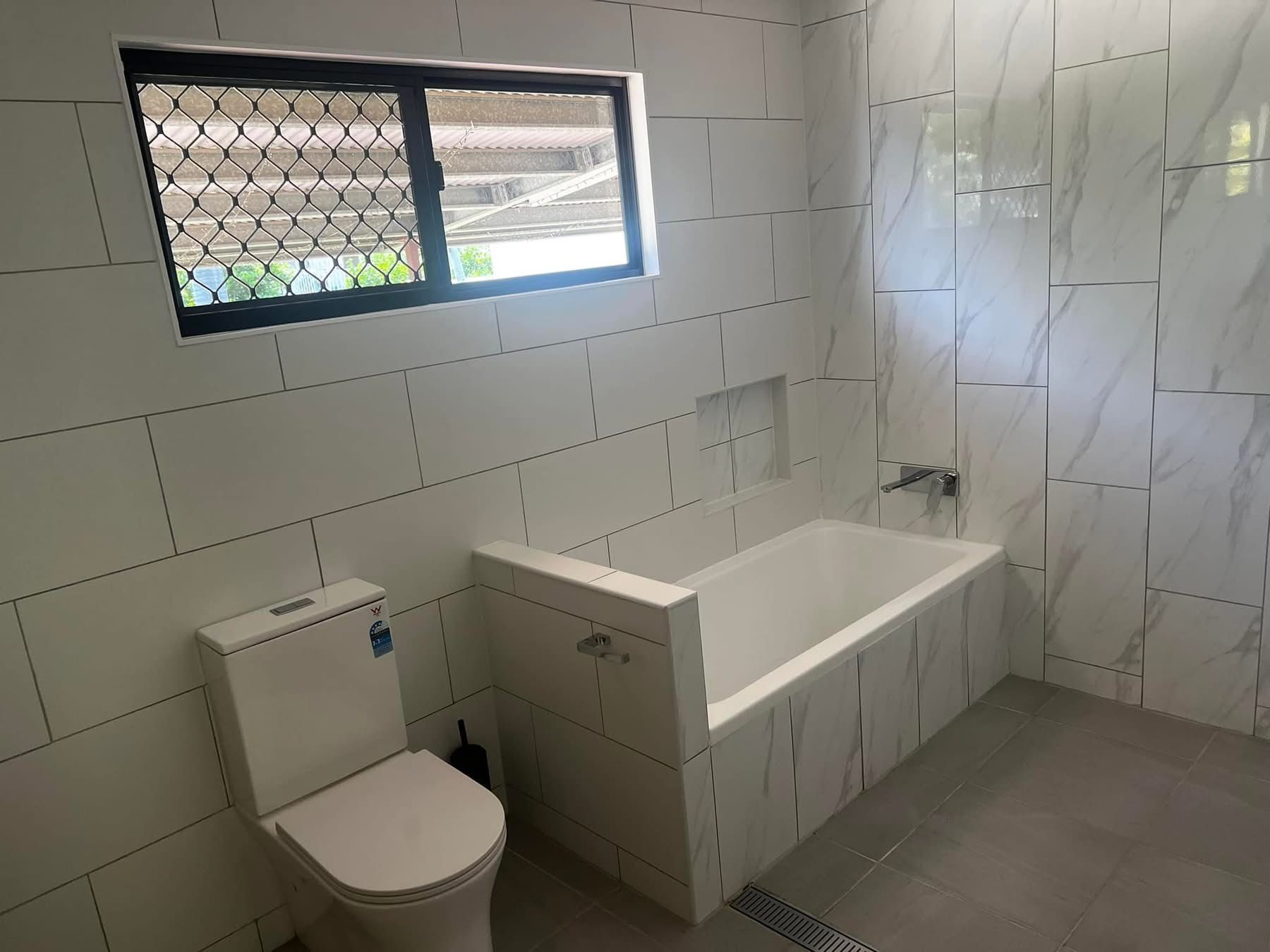A Bathroom With A Toilet , Bathtub , Shower And Window — Miss Bright Cleaning Services In Mount Isa City, QLD