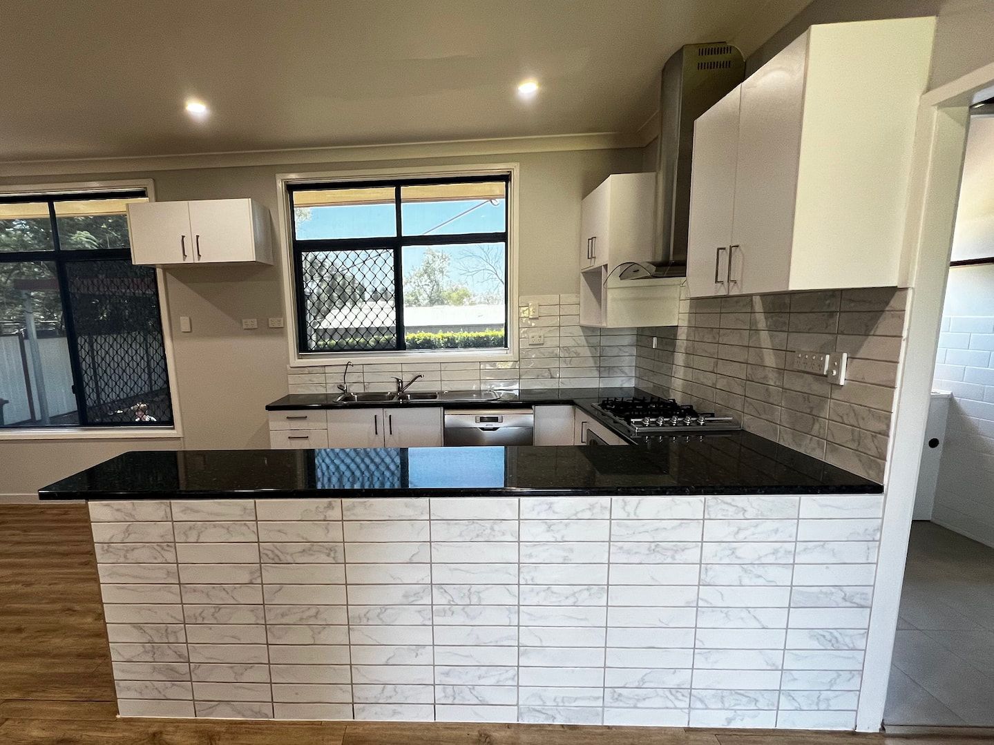 A Black Stove Top Oven is Sitting on a Kitchen Counter — Miss Bright Cleaning Services In Mount Isa City, QLD A Kitchen With White Cabinets And A Black Counter Top — Miss Bright Cleaning Services In Mount Isa City, QLD