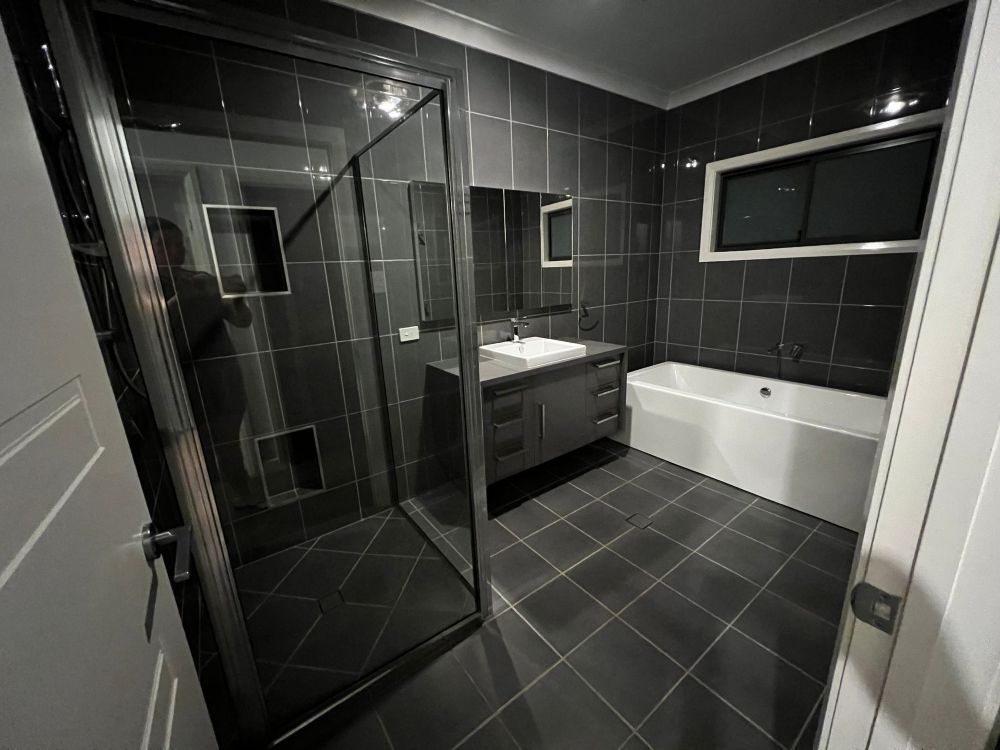 A Bathroom With Black Tiles, a Sink, and a Bathtub — Miss Bright Cleaning Services In Mount Isa City, QLD