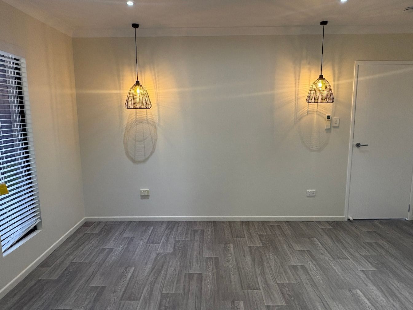 An Empty Room With A Gray Floor And Two Pendant Lights Hanging From The Ceiling — Miss Bright Cleaning Services In Mount Isa City, QLD