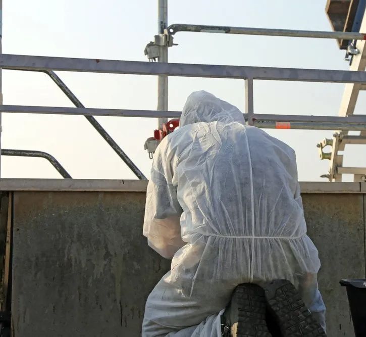 A Man in a White Coverall is Kneeling Down — Ron Nickel Roofing in Tweed Heads South, NSW
