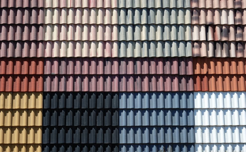 Assorted colored roof tiles arranged in horizontal rows, showcasing a variety of colours.